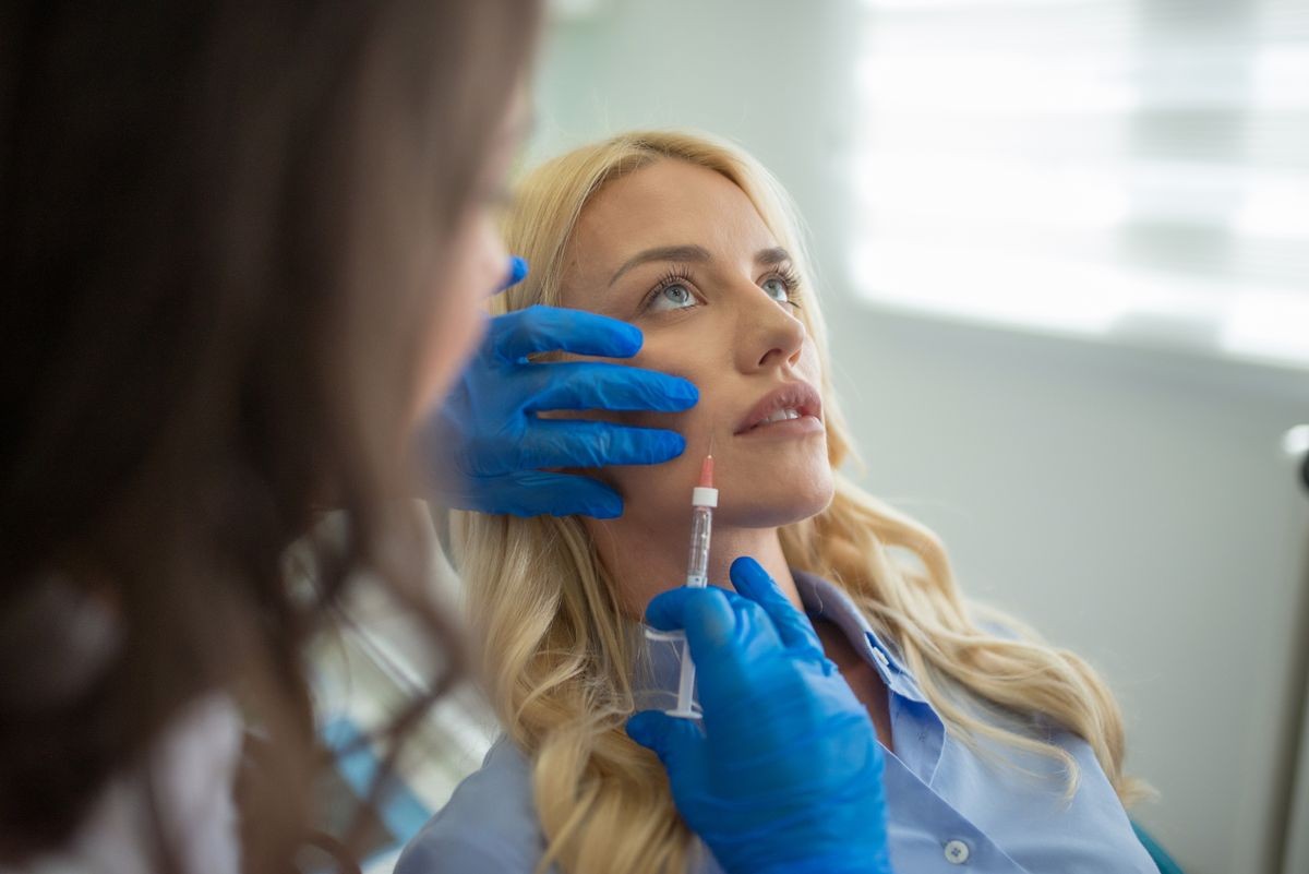 Cosmetologist making botox injection in female lips